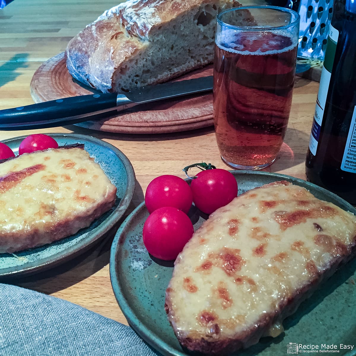 two plates of welsh rarebit served with cherry tomatoes. Beer and bread behind.
