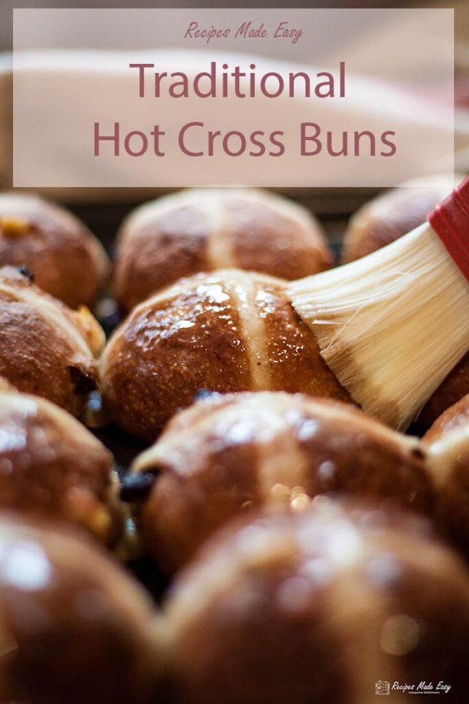 hot cross buns being brushed with glaze.
