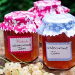 2 jars of whitecurrant jam with fresh whitecurrants in front.