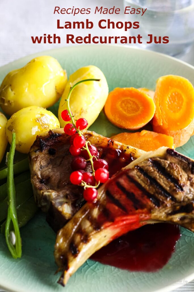 2 lamb chop with redcurrant jus on top garnished with a sprig of fresh redcurrants and served with potatoes and carrots.