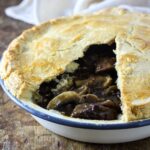 steak mushroom and ale pie with portion of crust removed to show filling.