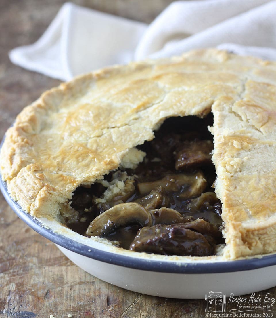 Steak mushroom and ale pie with a portion of the crust removed to show filling.