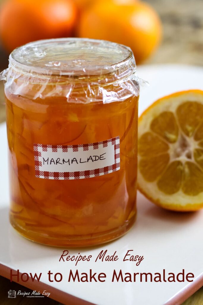 jar of marmalade with seville oranges behind and cut orange on side.