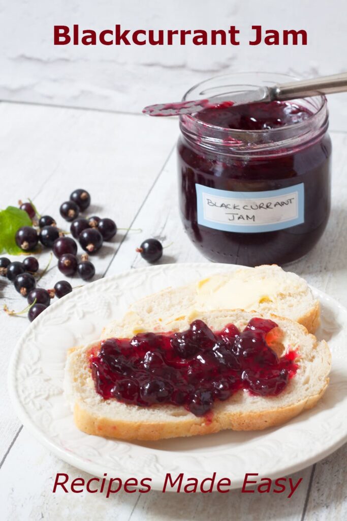 jar of blackcurrant jam in background with slice of bread on a plate spread with jam in foreground.