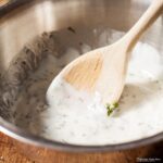 bowl of really easy yoghurt sauce with a wooden spoon.