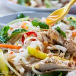 chicken noodle salad in bowl with dressing spooned over.
