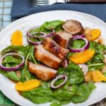 duck and orange salad on white plate.