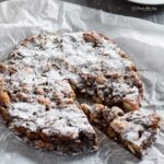panforte on crumpled parchment with wedge partly removed.
