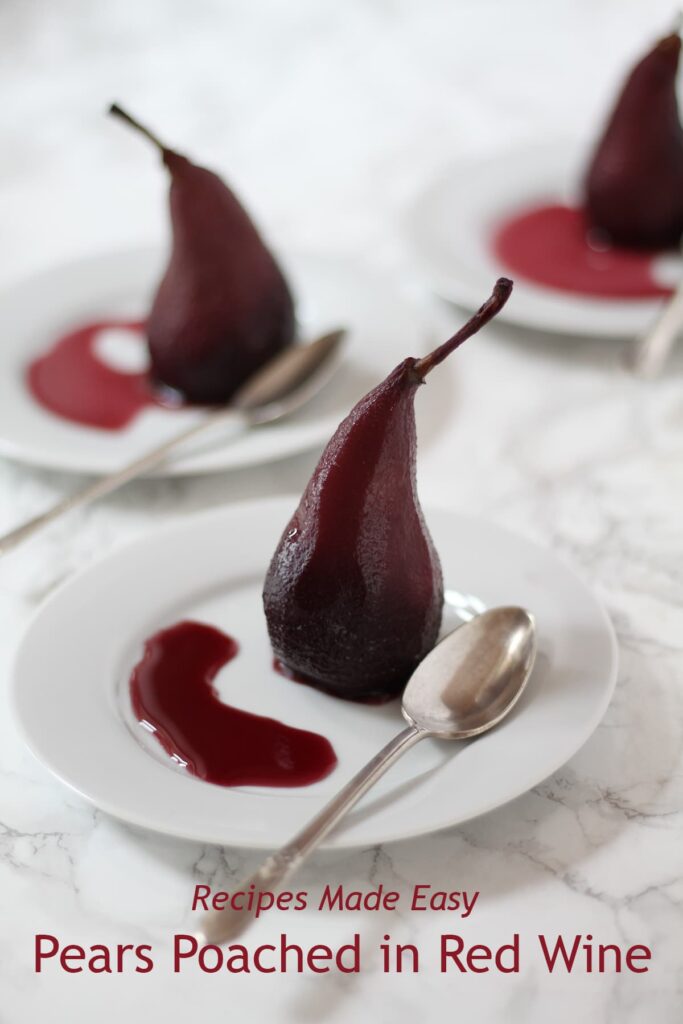 poached pear standing on a white plate with pool of syrup and a teaspoon. Two more serving behind.