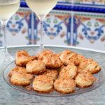 plate of Pogácsa with 2 glasses of wine behind.