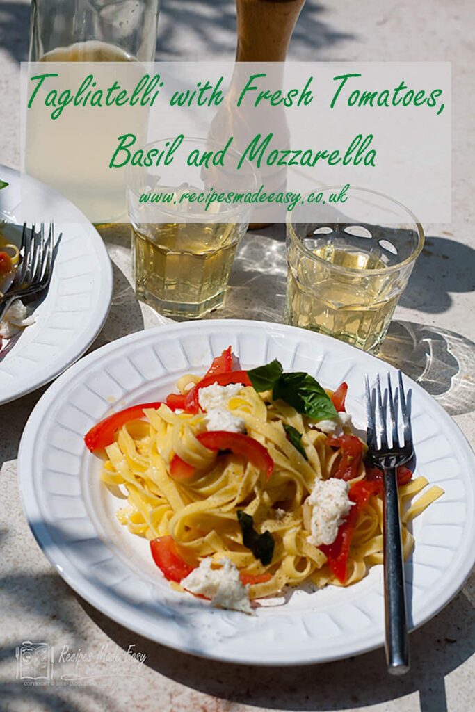 tagliatelli with tomatoes, mozzarella and basil on an outdoor table in sunshine.