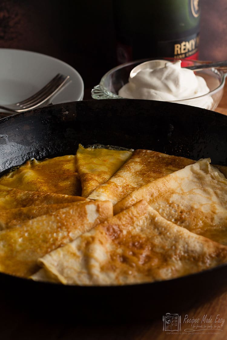 pancakes in a pan with bowl of cream behind