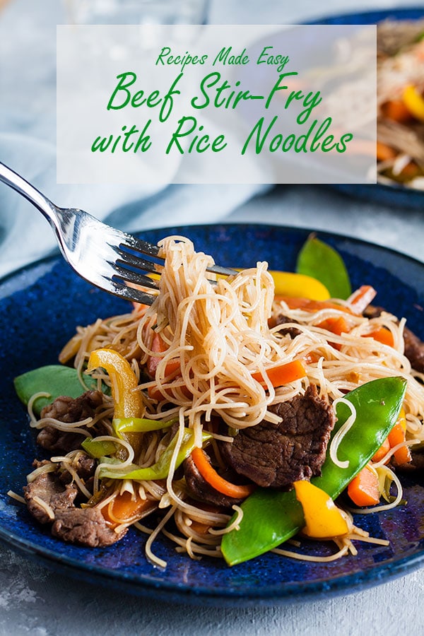 beef stir fry with rice noodles lifted on a fork.