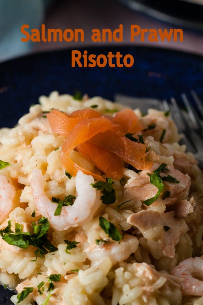 serving of salmon and prawn risotto garnished with parsley and smoked salmon.