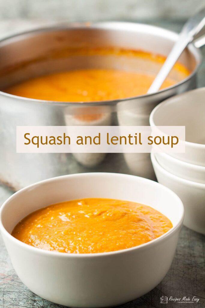 bowl of soup with saucepan and stack of bowls behind.