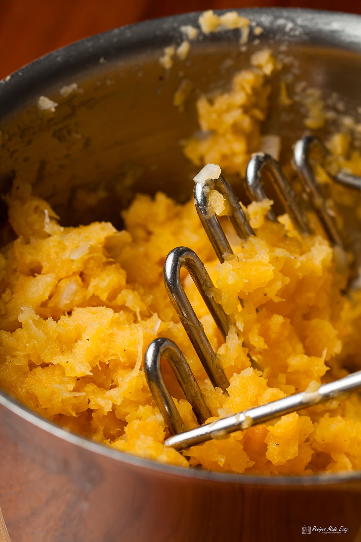 Close up of mashed swede in saucepan with potato masher
