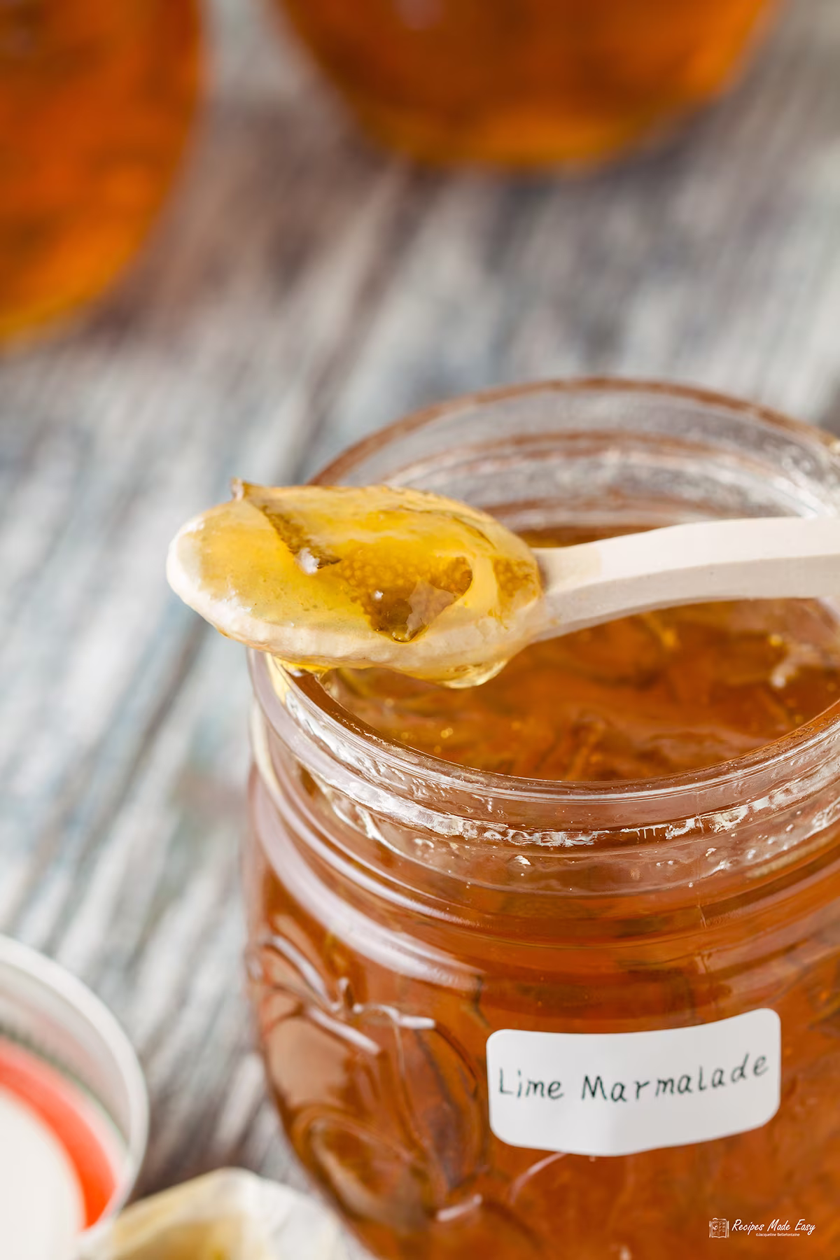 open jar of lime marmalade with spoon of marmalade resting on top.